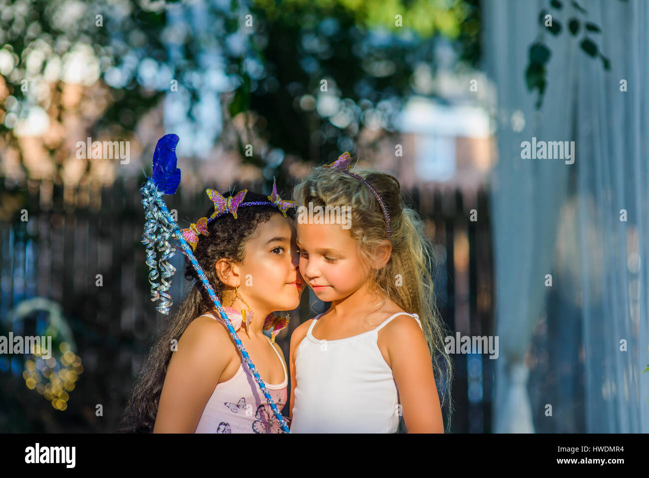 Two young girls dressed as fairies, girl whispering in friend's ear Stock Photo