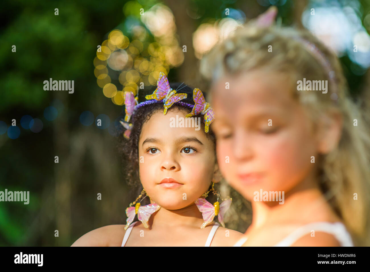 Two young girls, outdoors, wearing butterflies in hair Stock Photo