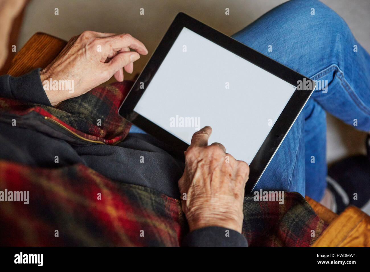 Senior woman sitting in chair, using digital tablet, elevated view Stock Photo