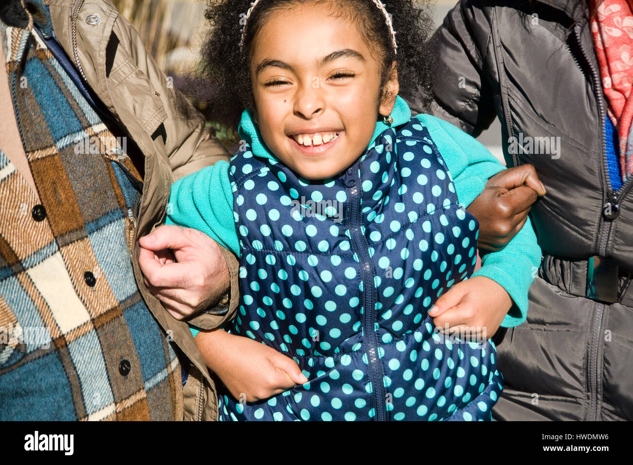 Smiling girl linking arms with parents Stock Photo