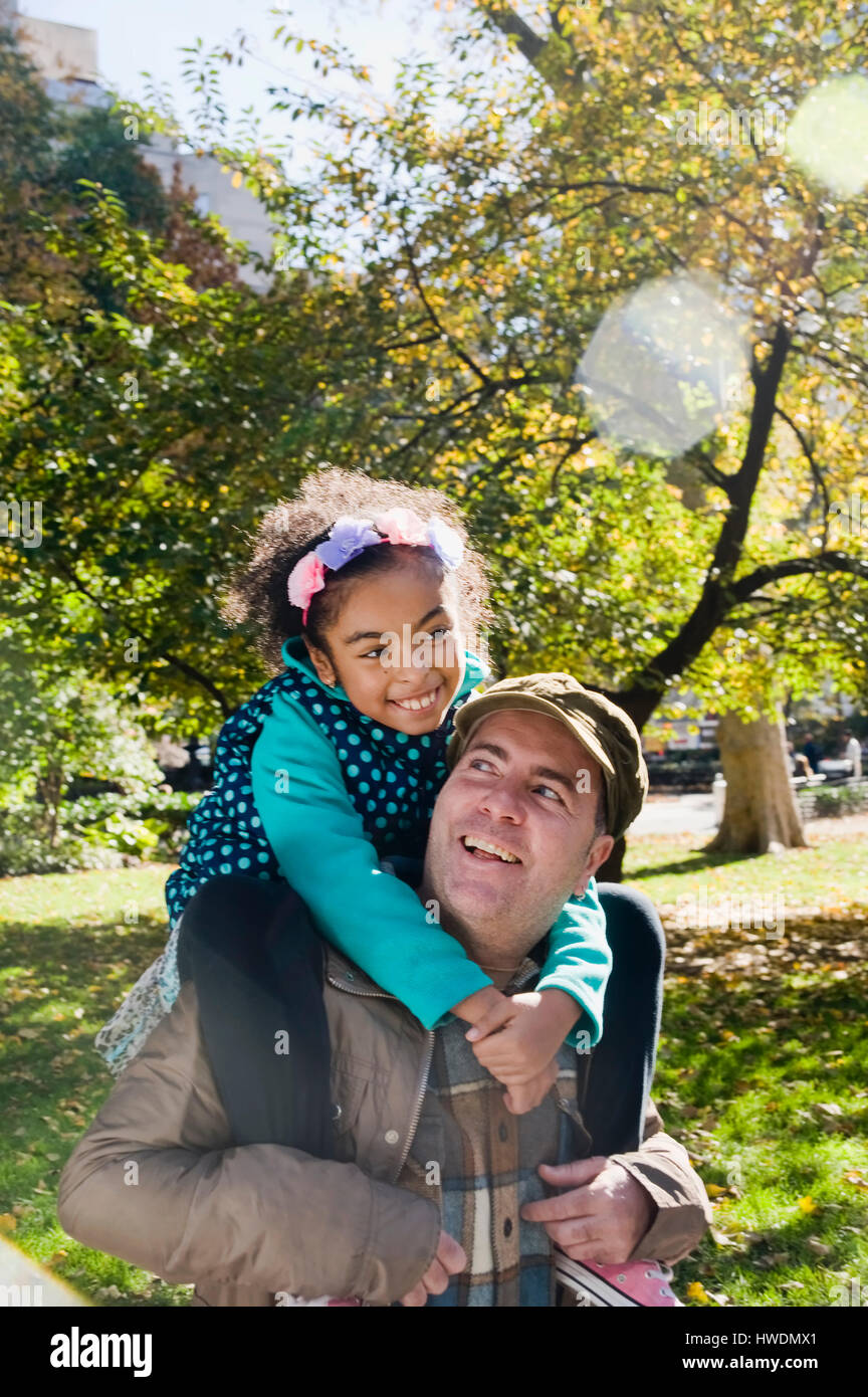 Father giving smiling daughter piggy back Stock Photo