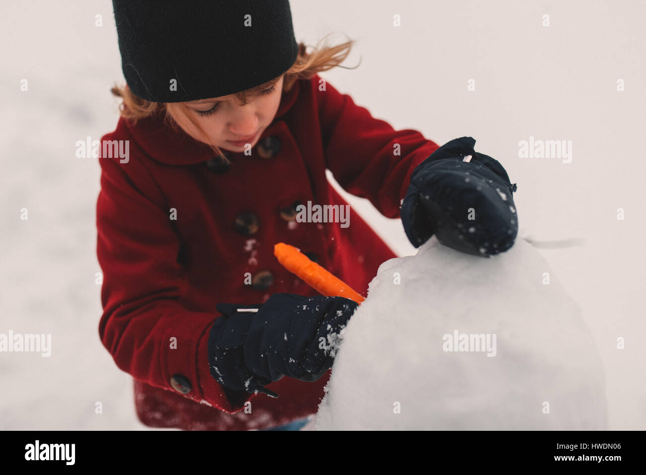 Girl using carrot for snowman's nose Stock Photo