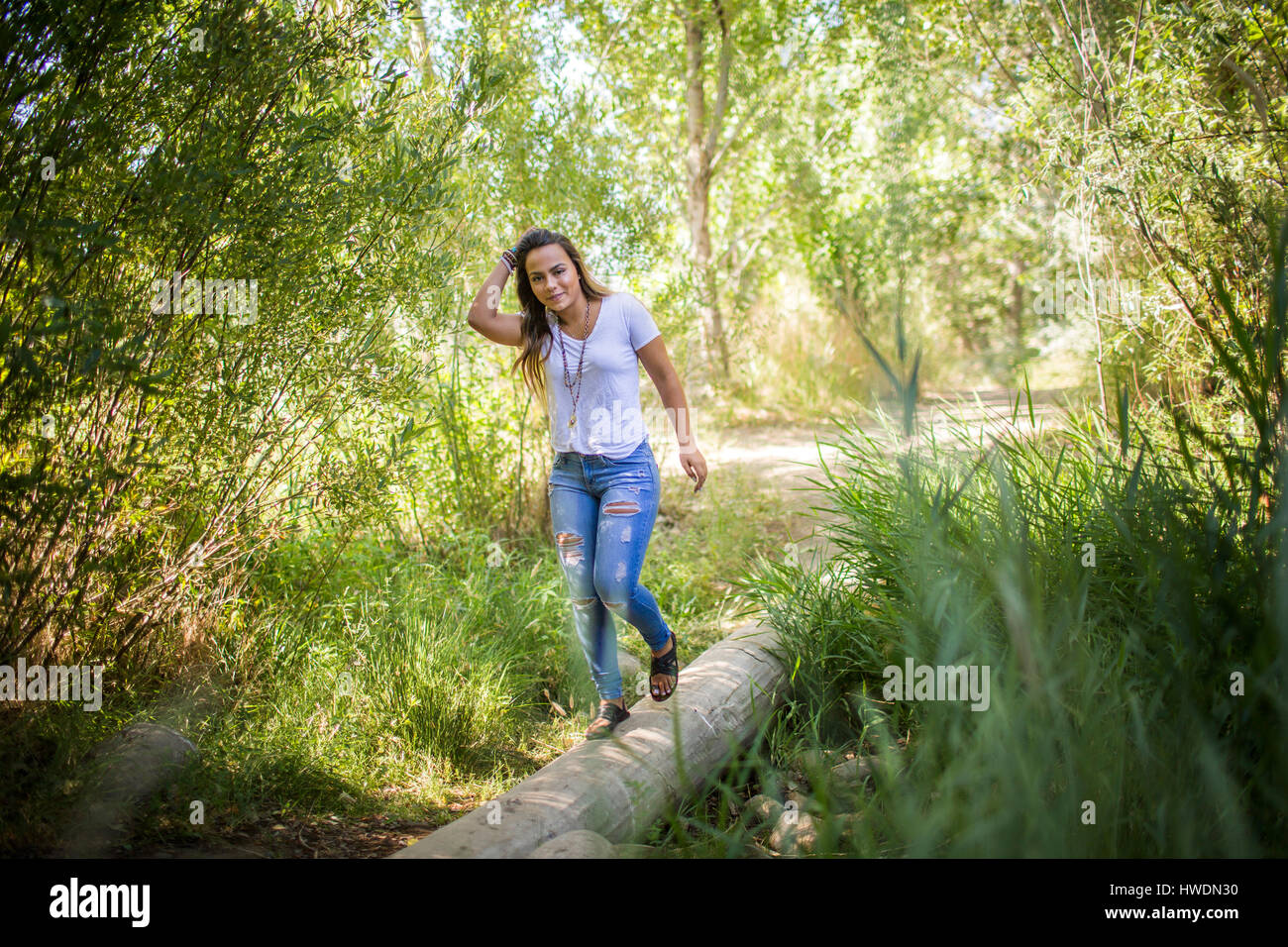 Portrait of teenage girl stepping across log in woodland Stock Photo