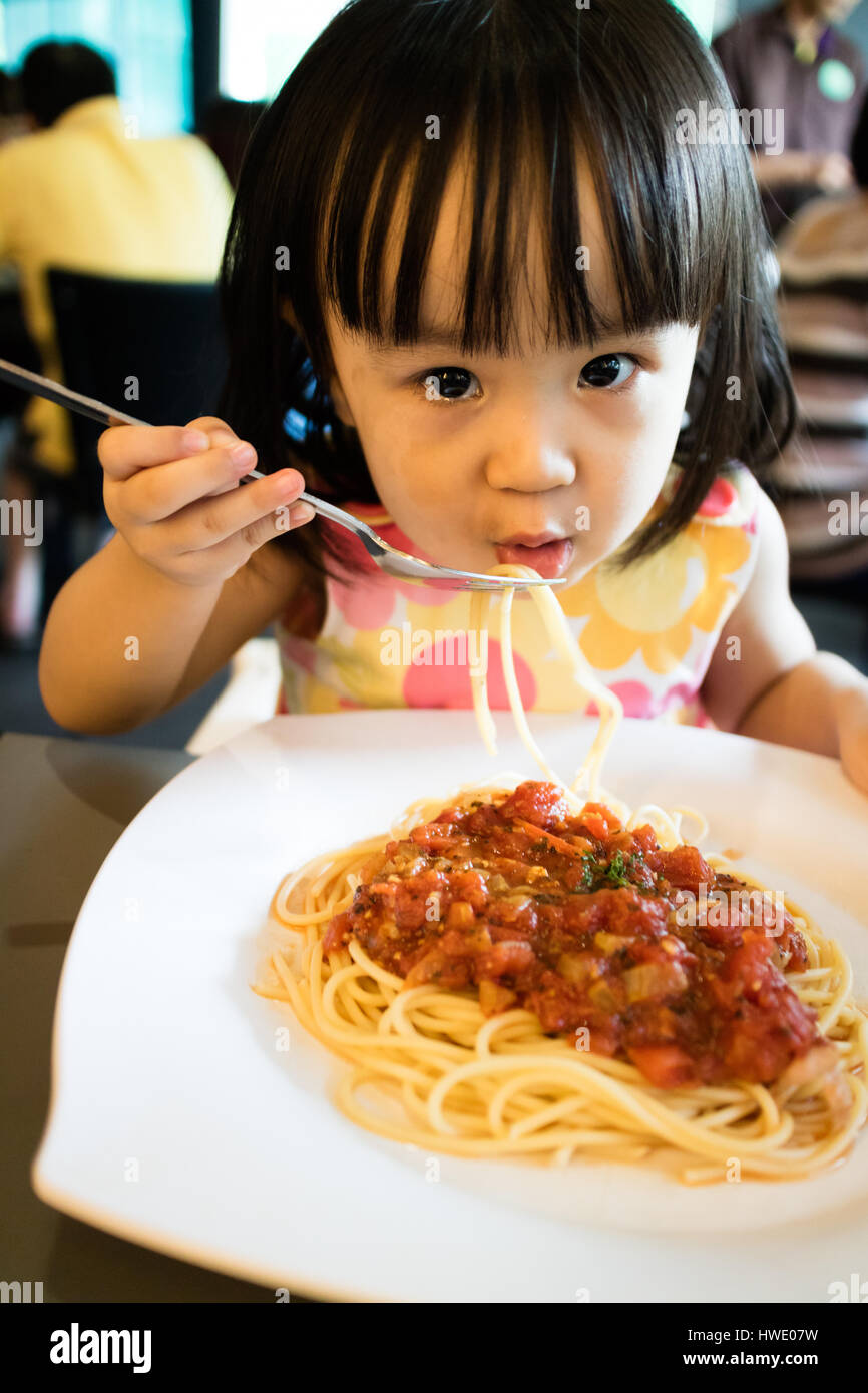 asian-little-chinese-girl-eating-spaghetti-in-a-restaurant-HWE07W.jpg