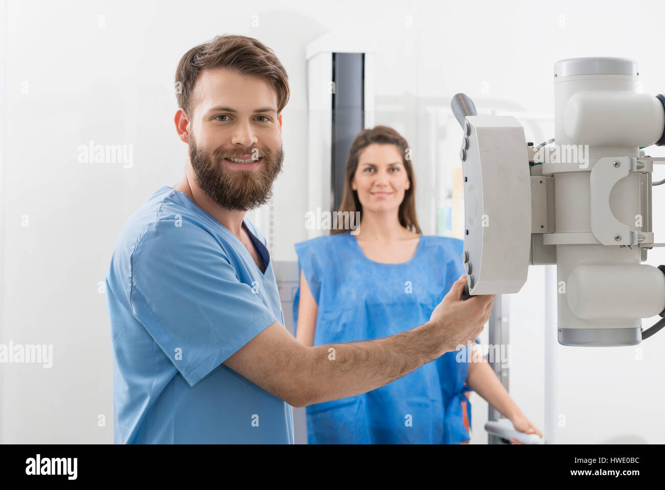 Radiologist Adjusting X-ray Machine Over Female Patient In Hospi Stock Photo