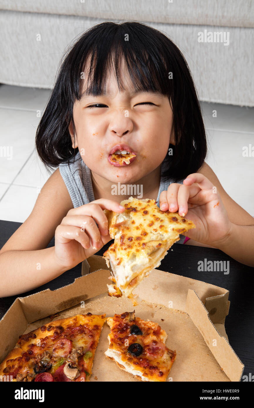 Asian Little Chinese Girl Eating Pizza at Home Stock Photo