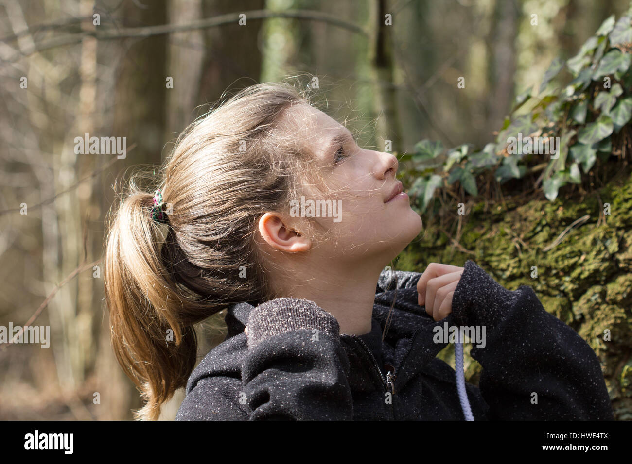 A pretty girl looks up in forest Stock Photo