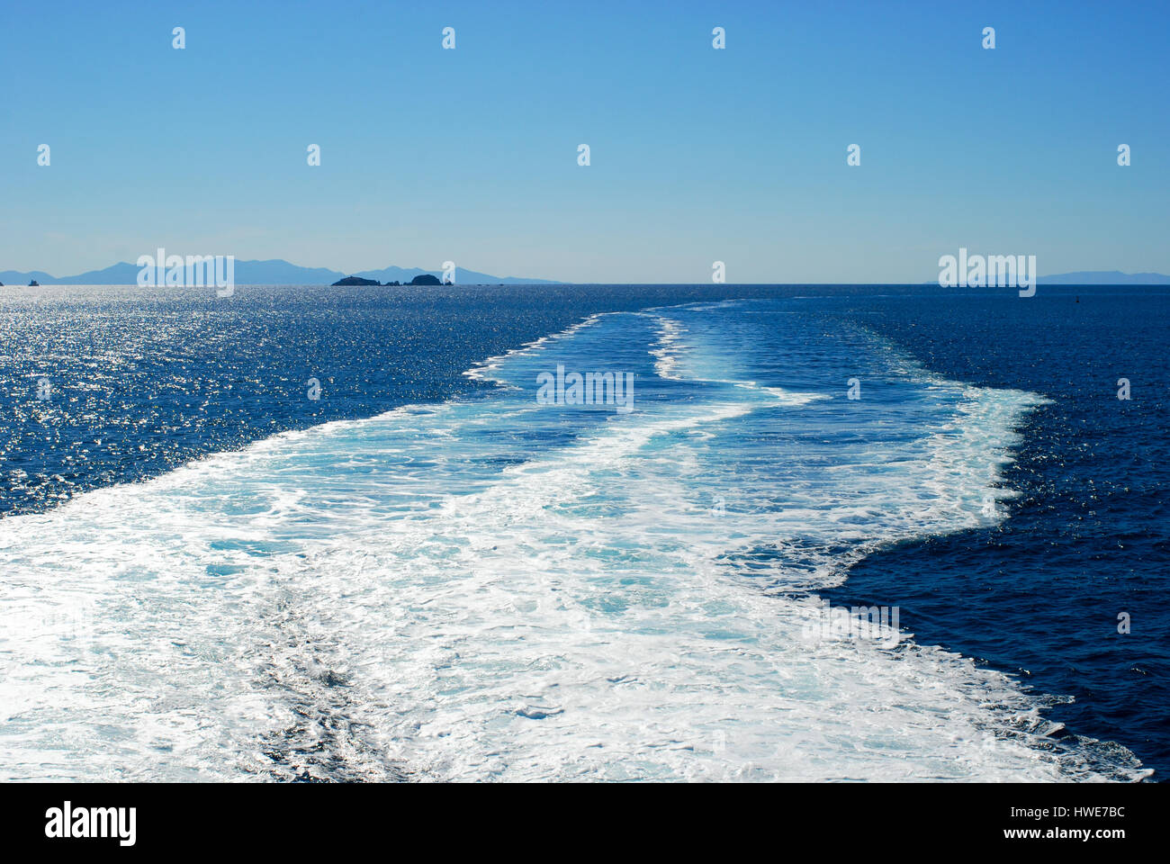 White wash from a Greek ferry contrasts with the deep blue Aegean Sea. Stock Photo