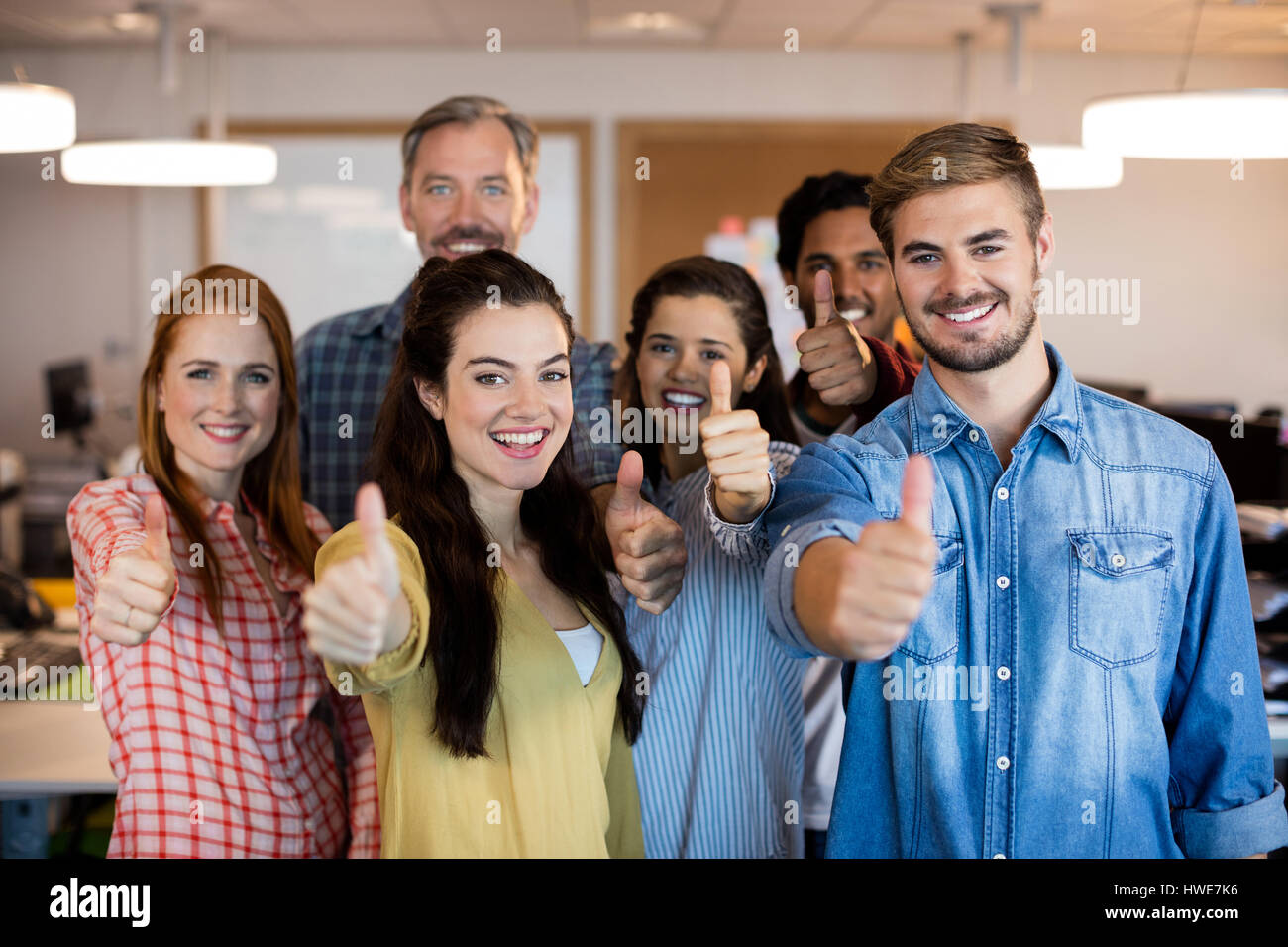 Happy creative business team showing thumbs up at office Stock Photo ...