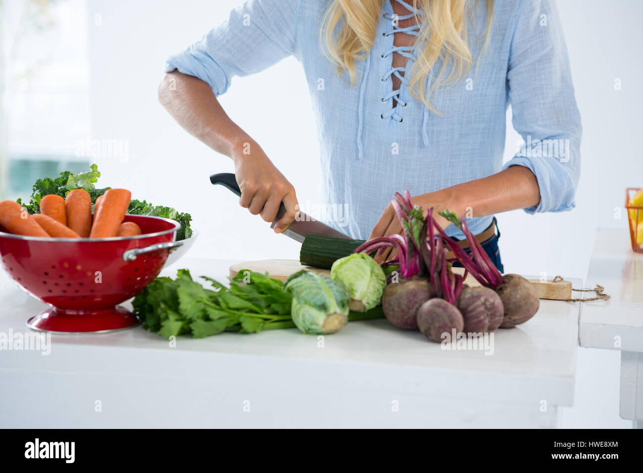 Mid-section of woman cutting vegetables on chopping board against white background Stock Photo
