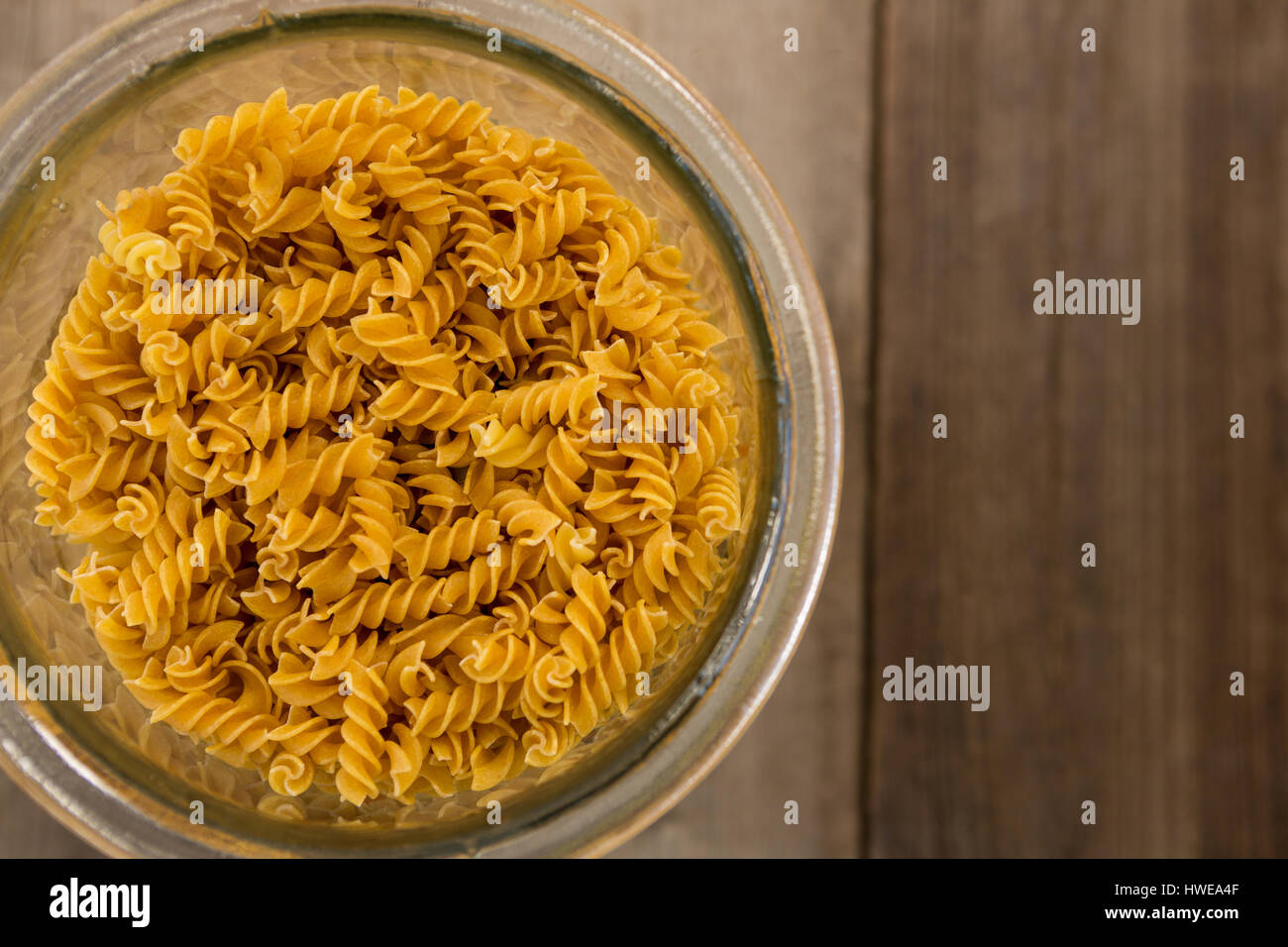 Girandole pasta in a glass container on wooden surface Stock Photo
