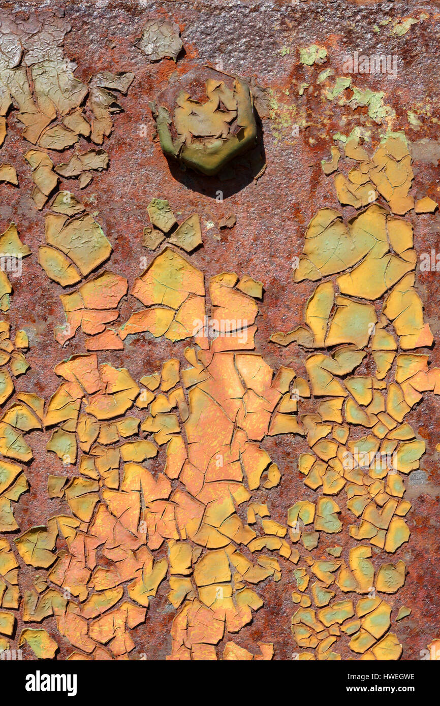 Rusty steel hangar door with several layers of paint cracked and peeling off,detail includes a large hexagonal bolt head. several colours of paint. Stock Photo