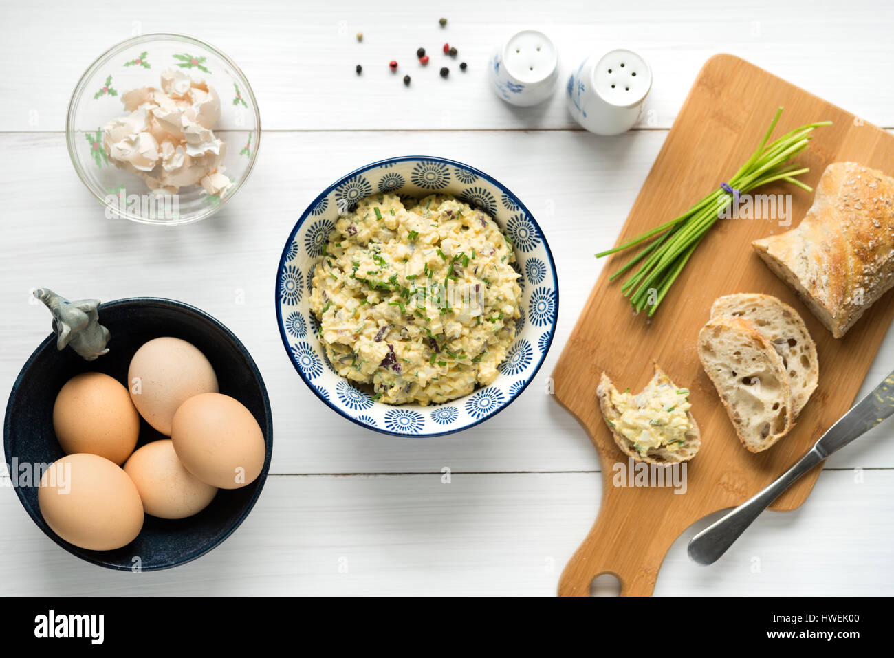 Homemade egg salad spread with mayonnaise, mustard, red onion sprinkled with chives, top view background on white table. Stock Photo