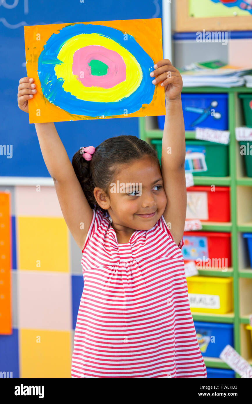 Preschool girl holding colourful circle painting in classroom Stock Photo