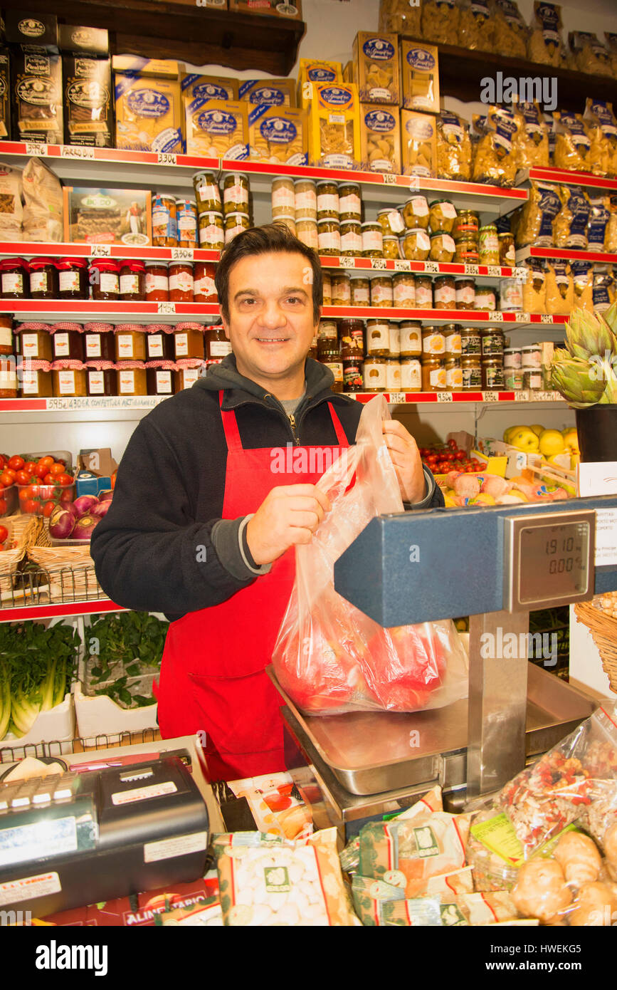 Portrait of male grocer weighing red peppers in local italian grocery shop Stock Photo