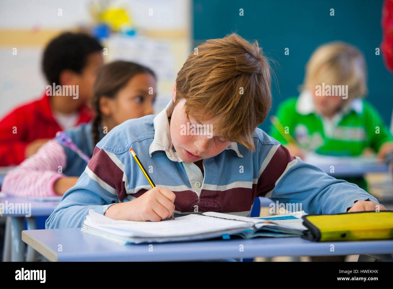 Primary schoolboy writing in classroom Stock Photo