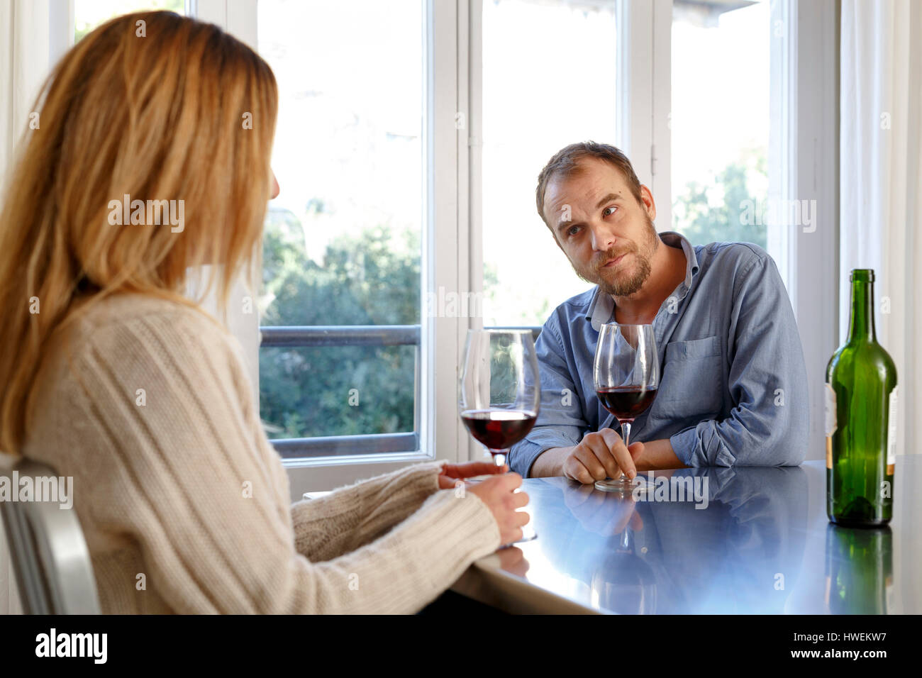 Mid adult couple at home, drinking glass of wine, having disagreement Stock Photo