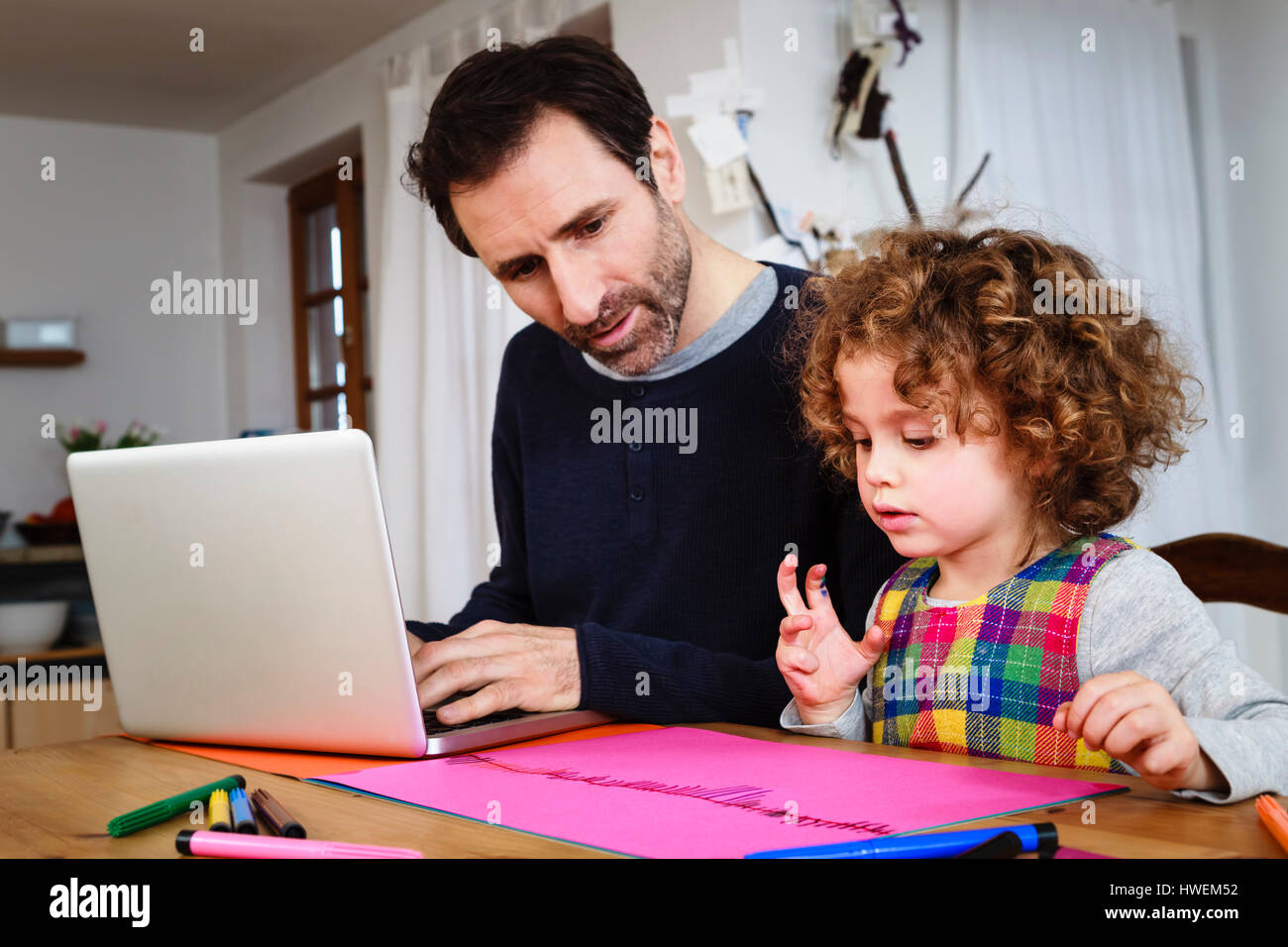 Girl drawing at table while father using laptop Stock Photo - Alamy