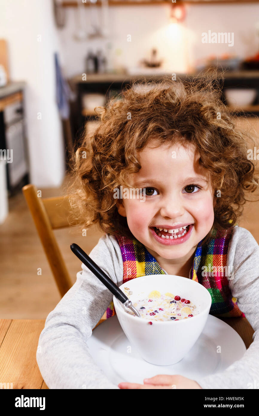 Portrait of girl with toothy grin having cereal in kitchen Stock Photo