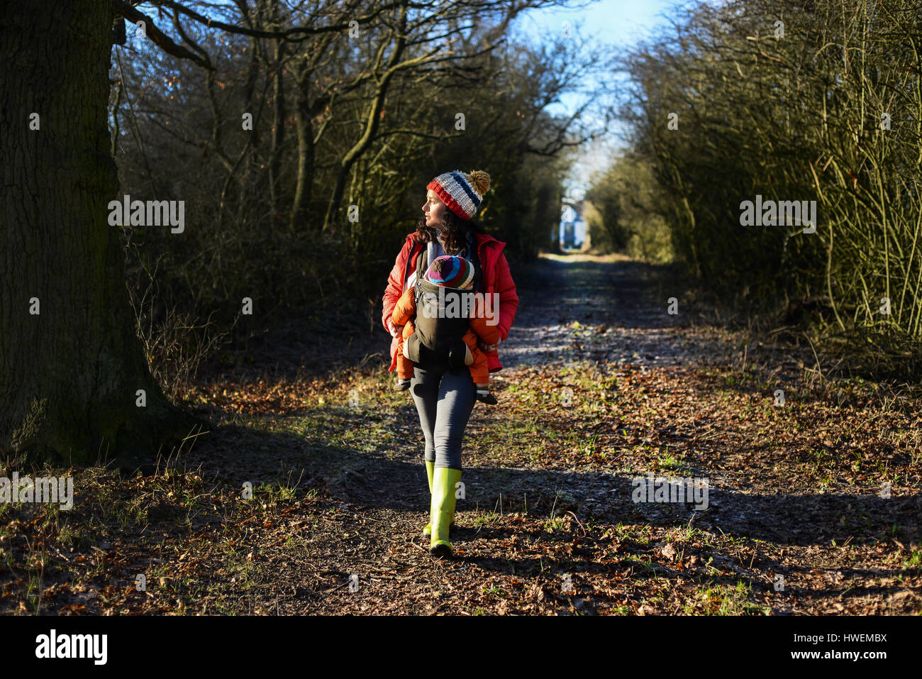 Woman walking along country path, carrying young baby in sling Stock Photo