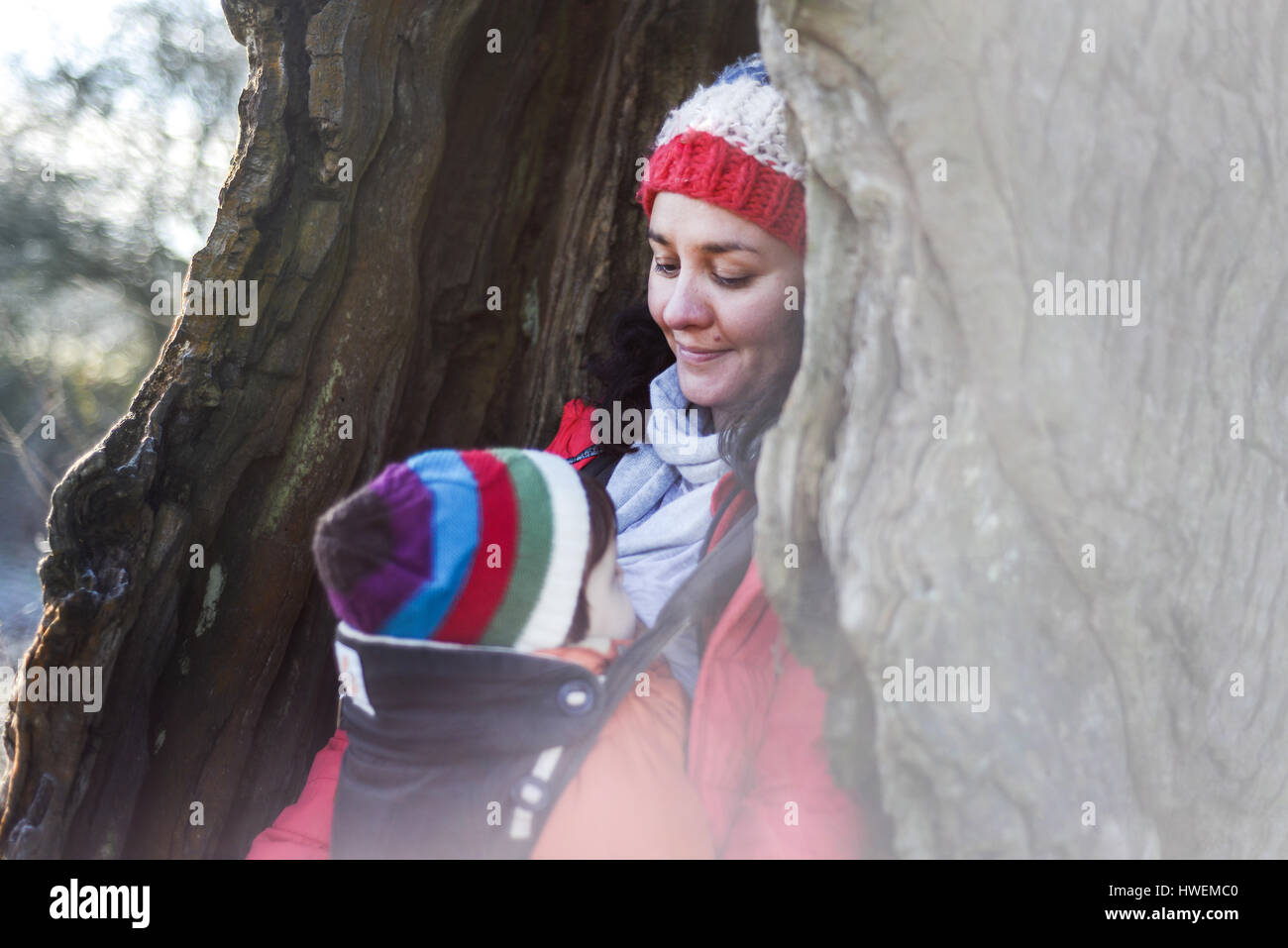 Woman in hollow tree, carrying young baby in sling Stock Photo