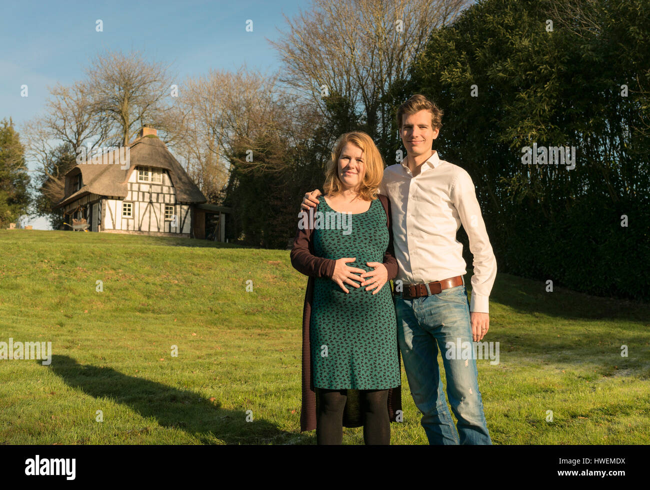 Portrait of mid adult couple, expecting baby,  woman holding stomach Stock Photo