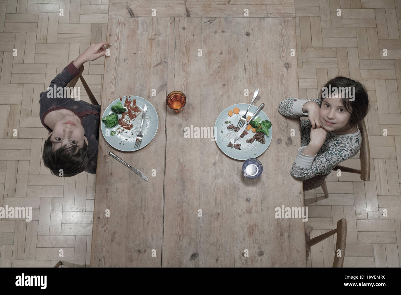 Overhead portrait of sister and brother eating dinner at kitchen table