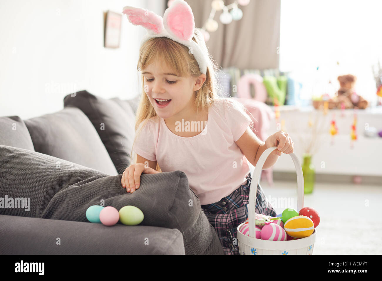 Girl finding easter eggs on sofa Stock Photo