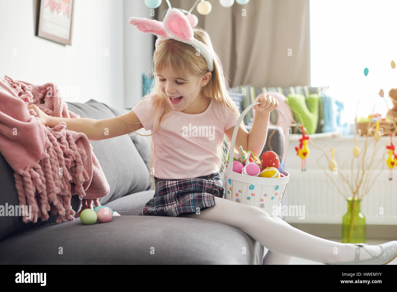Girl finding easter eggs under sofa blanket Stock Photo Alamy