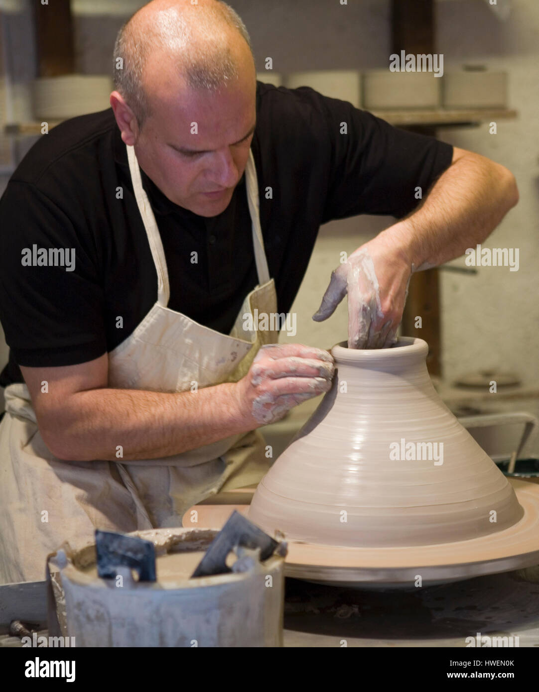 Male potter shaping clay pot on pottery wheel in workshop Stock Photo ...