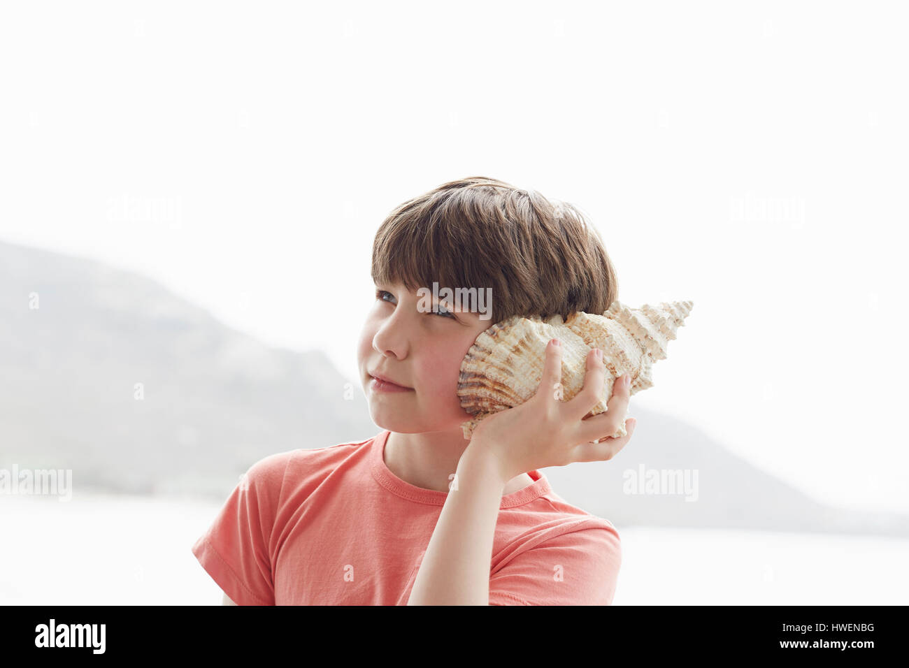 Boy holding seashell to ear, Kraalbaai, South Africa Stock Photo