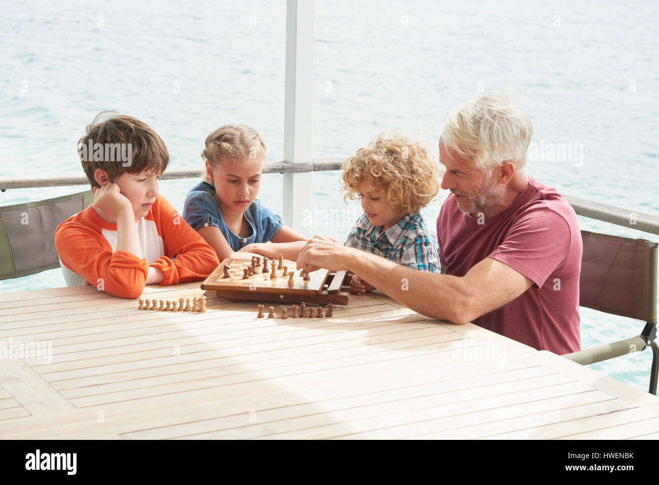 Grandfather and grandchildren playing chess Stock Photo