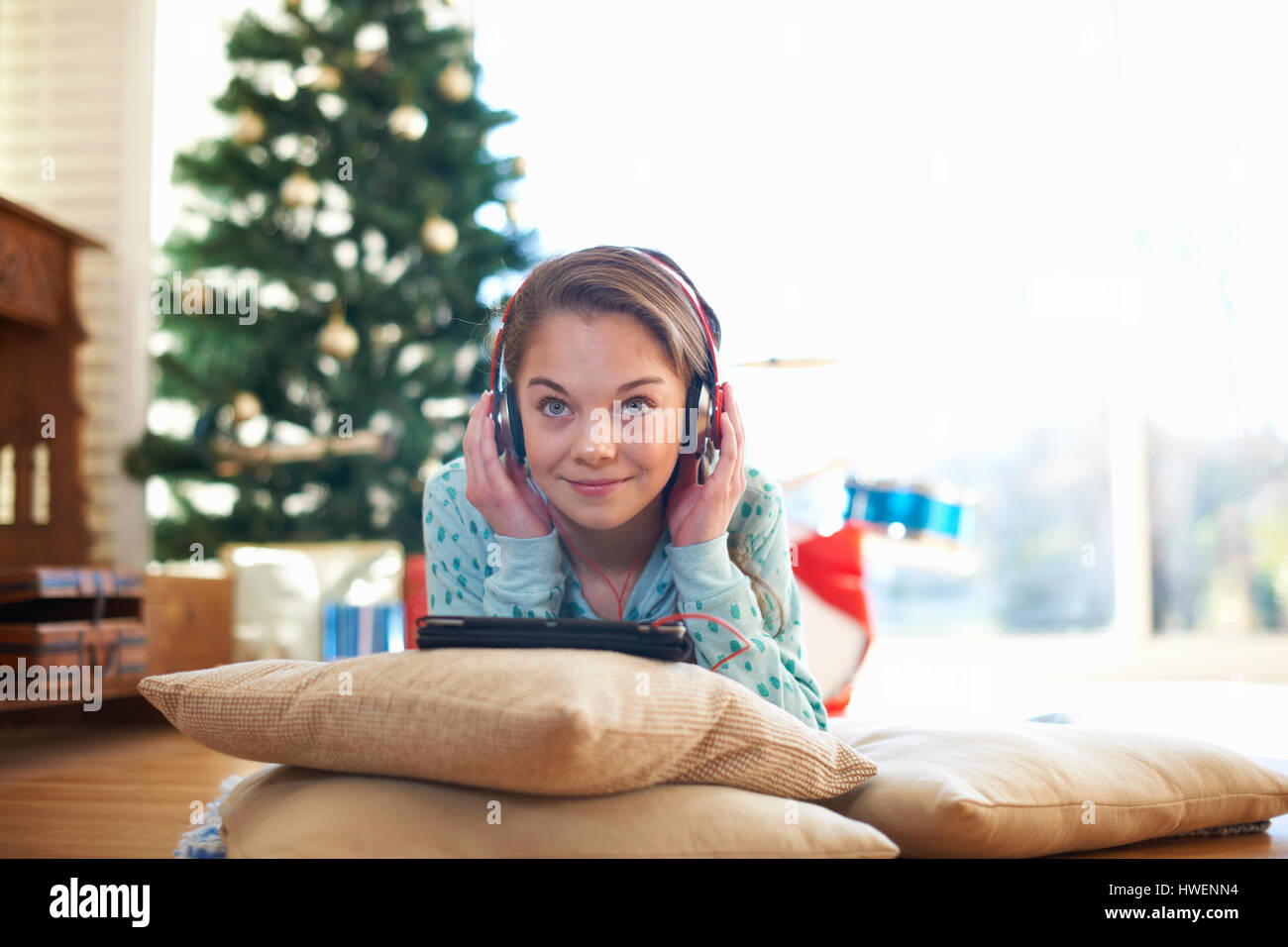 Girl lying on living room floor listening to headphones at Christmas Stock Photo
