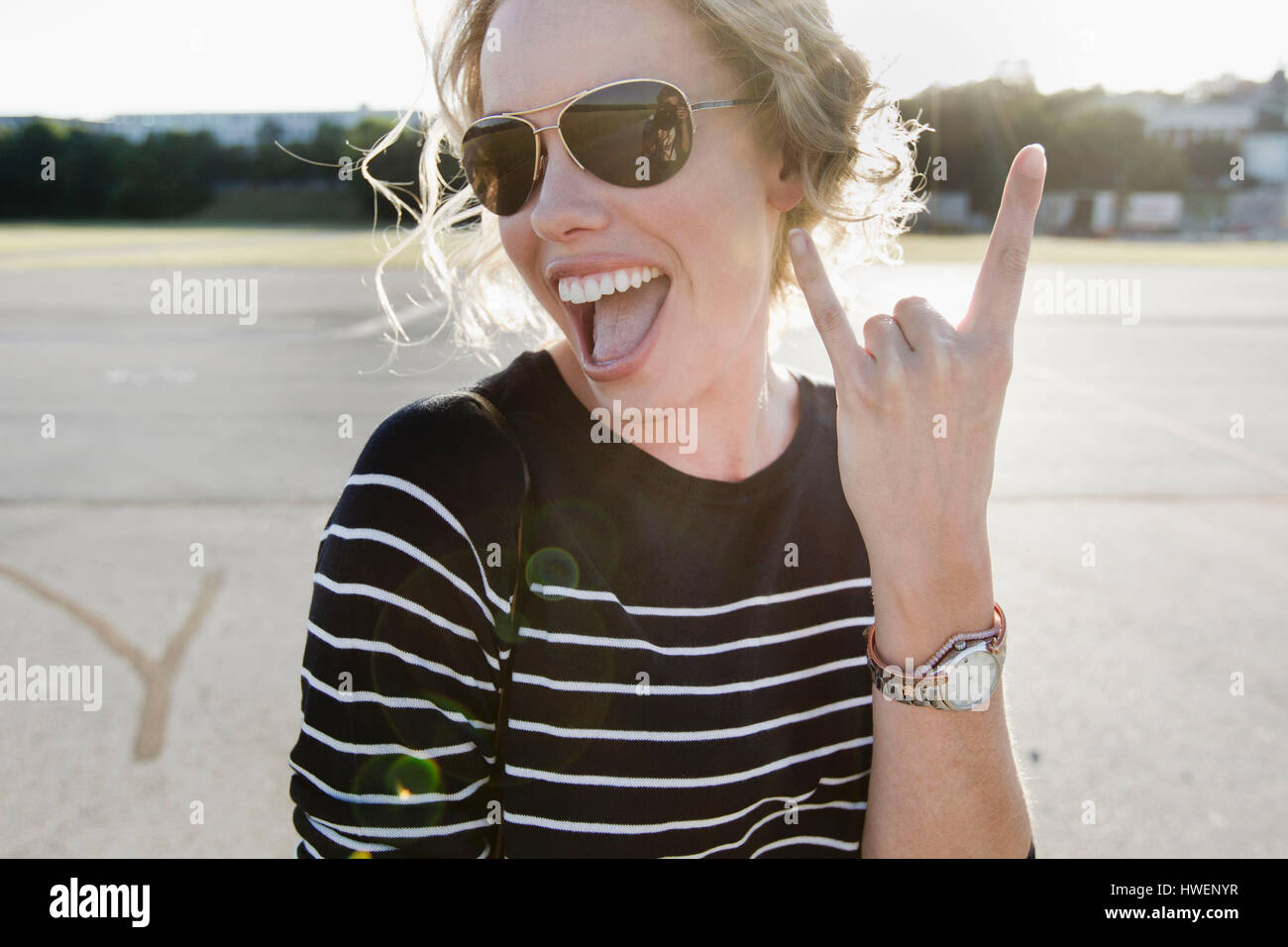 Portrait of mid adult woman wearing sunglasses making hand gesture Stock Photo