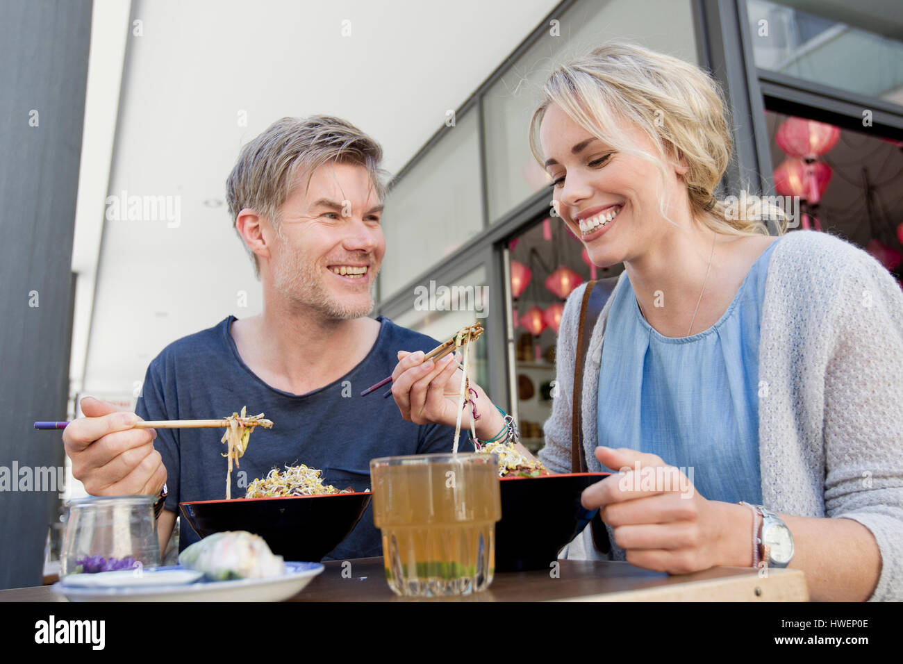 Couple eating noodles at city sidewalk cafe Stock Photo