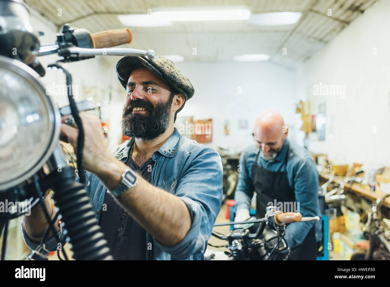 Two mature men, working on motorcycle in garage Stock Photo