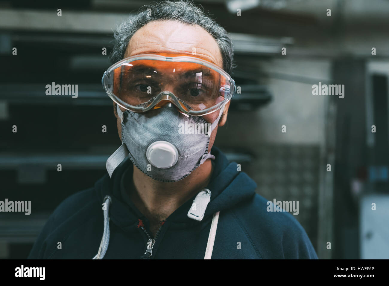 Portrait of metalworker in dust mask and safety goggles in forge workshop Stock Photo