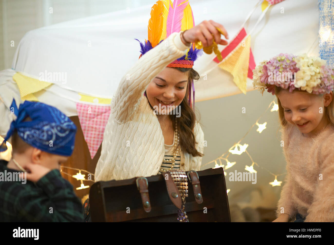 Boy and two sisters playing dress up from treasure chest Stock Photo