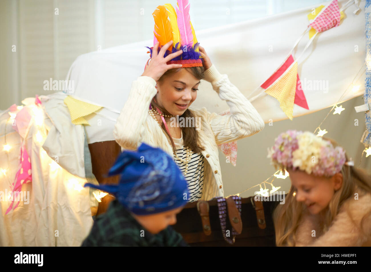 Boy and two sisters playing dress up from treasure chest Stock Photo