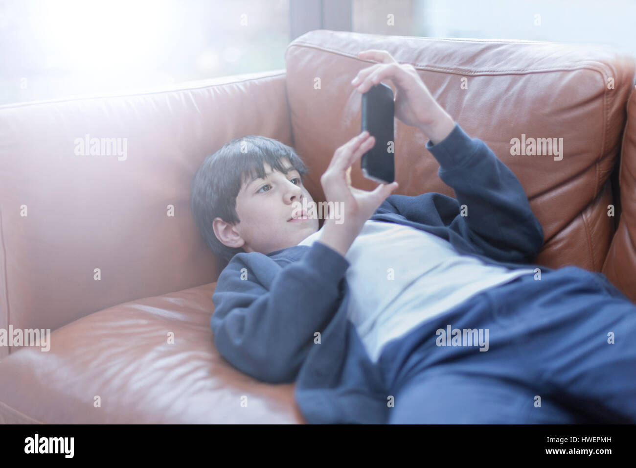 Boy playing with smartphone on sofa Stock Photo