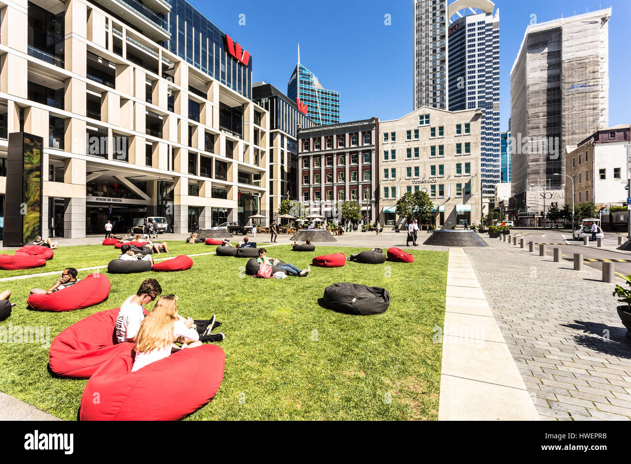AUCKLAND, NEW ZEALAND - MARCH 1, 2017: People relax on garden sofas in a park in Britomart in downtown in Auckland, New Zealand largest city on a sunn Stock Photo