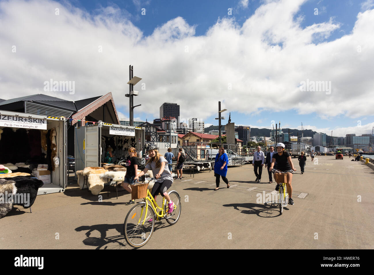 WELLINGTON, NEW ZEALAND - MARCH 2, 2017: Yound women ride biclycles in the street market in the Wellington waterfront promenade on a sunny summer day. Stock Photo
