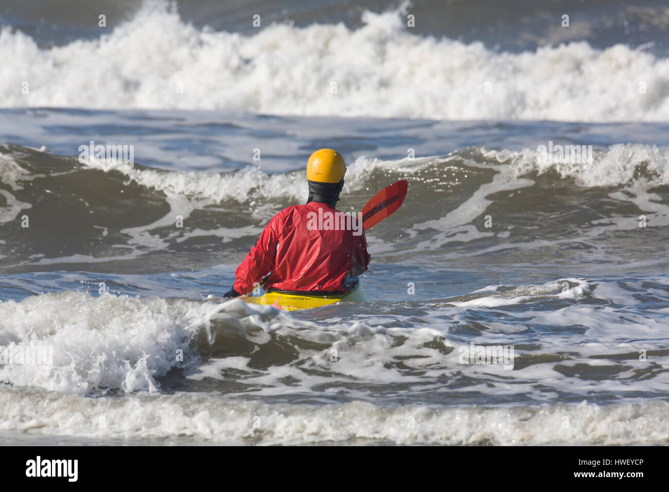 A surf kayaker paddles out into Pacific Ocean waves, Ocean Shores, WA