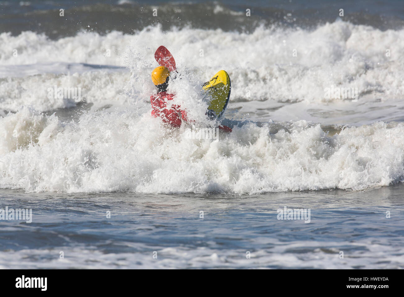 A Pacific Ocean wave breaks around a surf kayaker paddling out from the beach, Ocean Shores, WA. Stock Photo