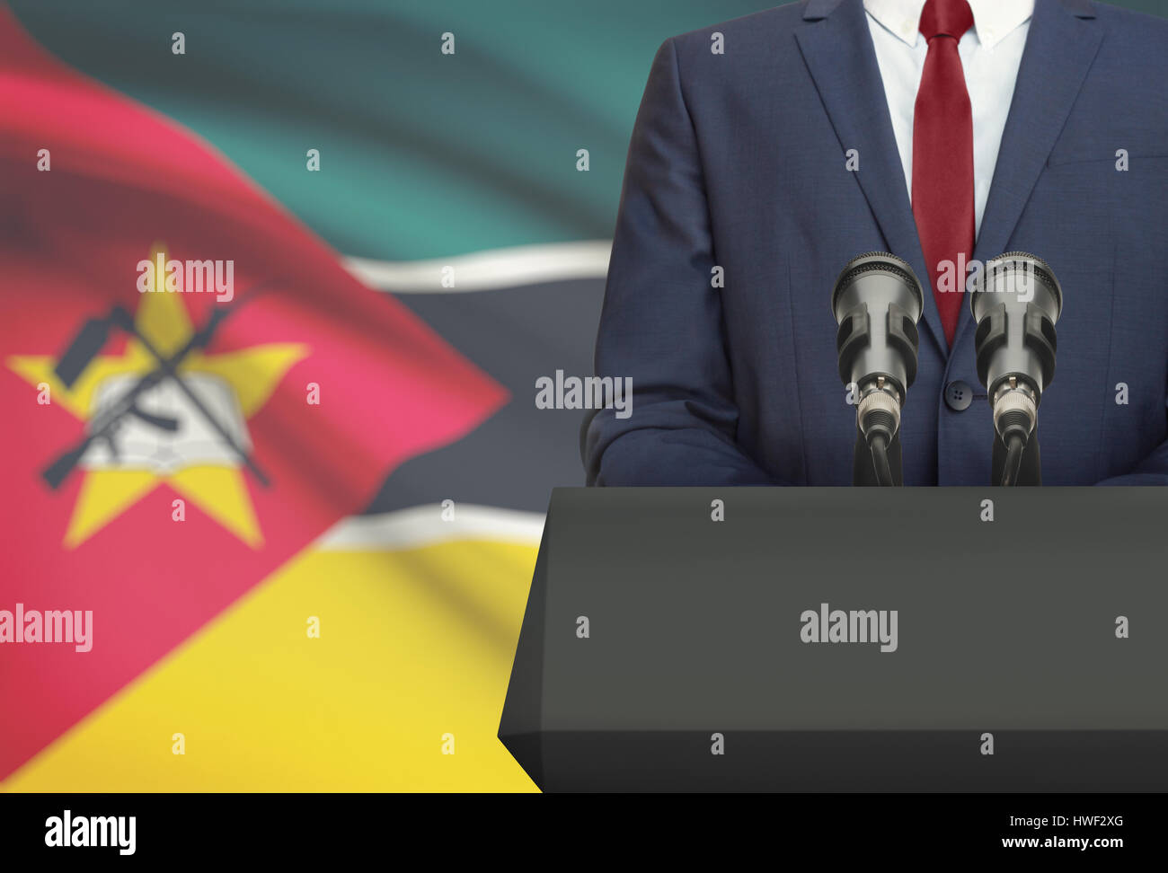 Businessman or politician making speech from behind the pulpit with national flag on background - Mozambique Stock Photo