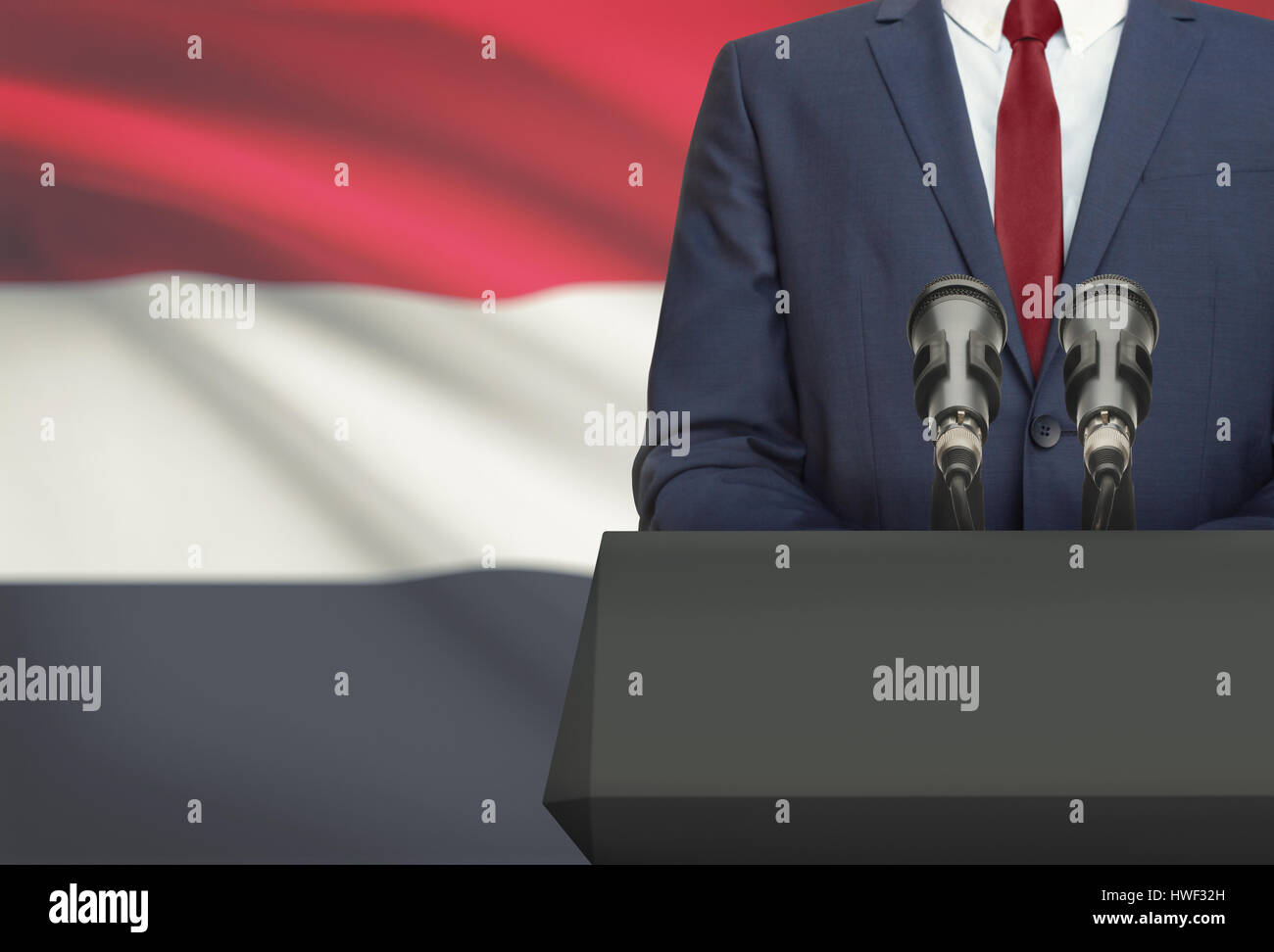 Businessman or politician making speech from behind the pulpit with national flag on background - Yemen Stock Photo