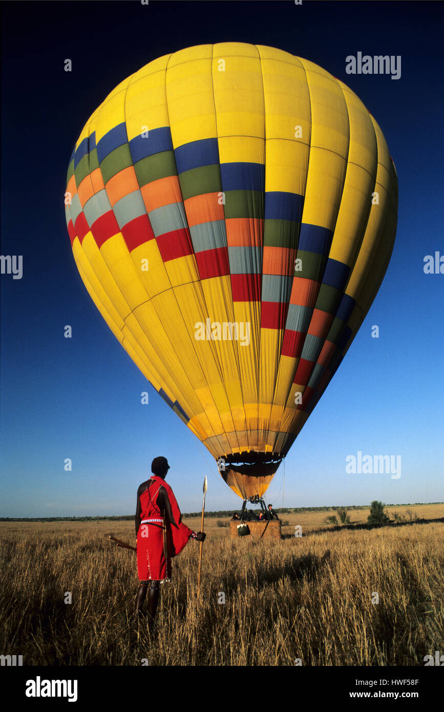 Masai tribesmen watching a hot air baloon take off, Masai Mara Game Reserve, Kenya Stock Photo