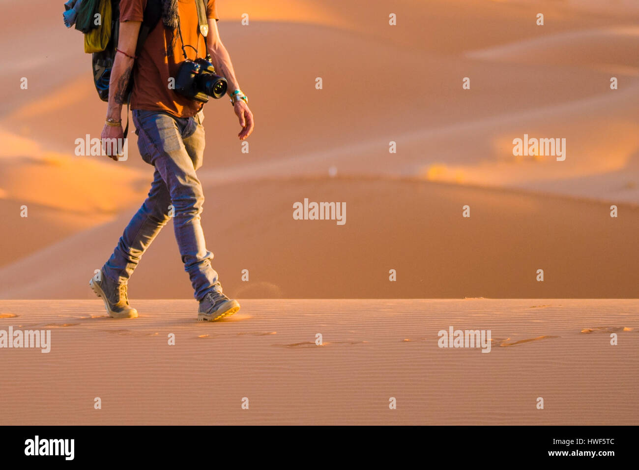 A man walks on the sahara desert dunes at sunset Stock Photo - Alamy