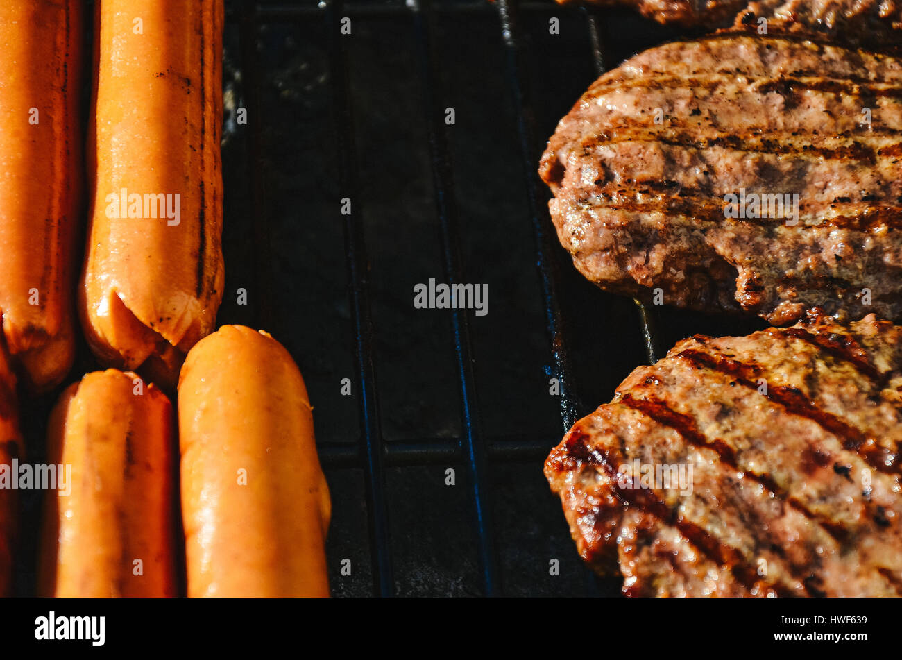 Cooking deli style hot dogs and hamburgers on a grill Stock Photo Alamy