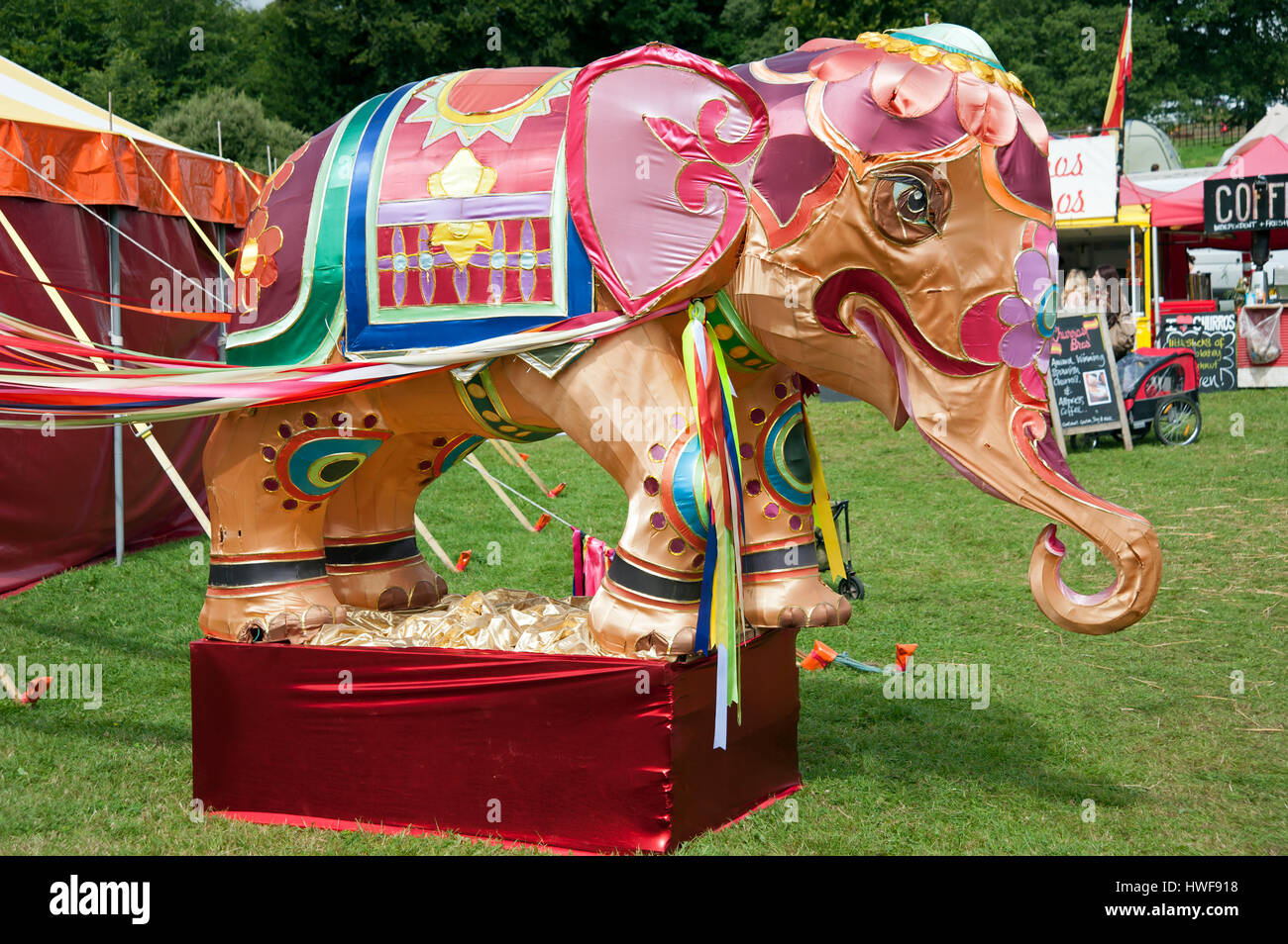 A large colourful silk covered elephant infant of tents and foods stalls at the Port Eliot Festival Cornwall Stock Photo